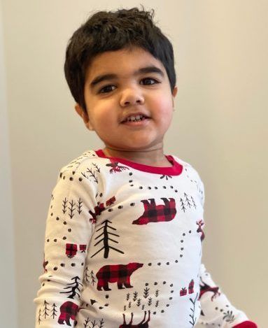 A young boy is wearing a pajama set with bears and trees on it.