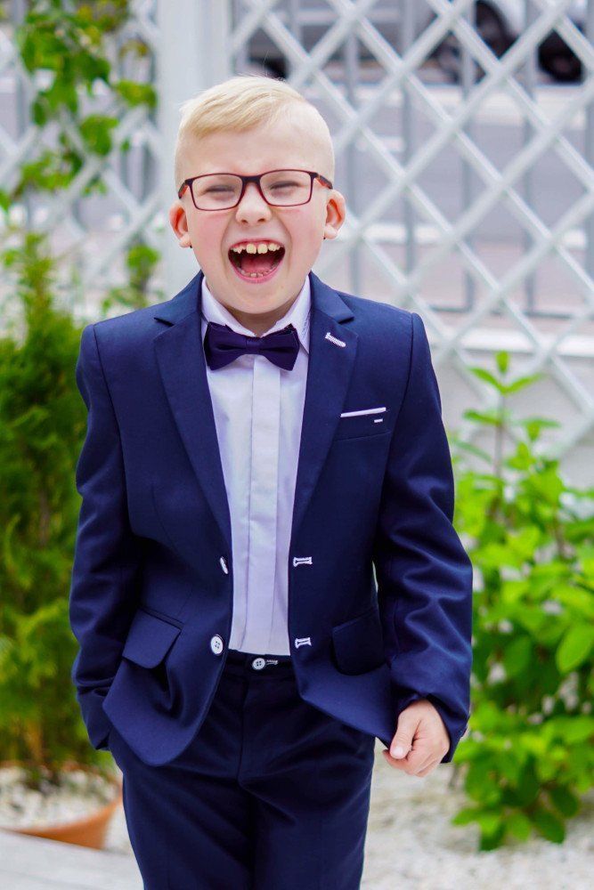 A young boy wearing a suit and bow tie is laughing.