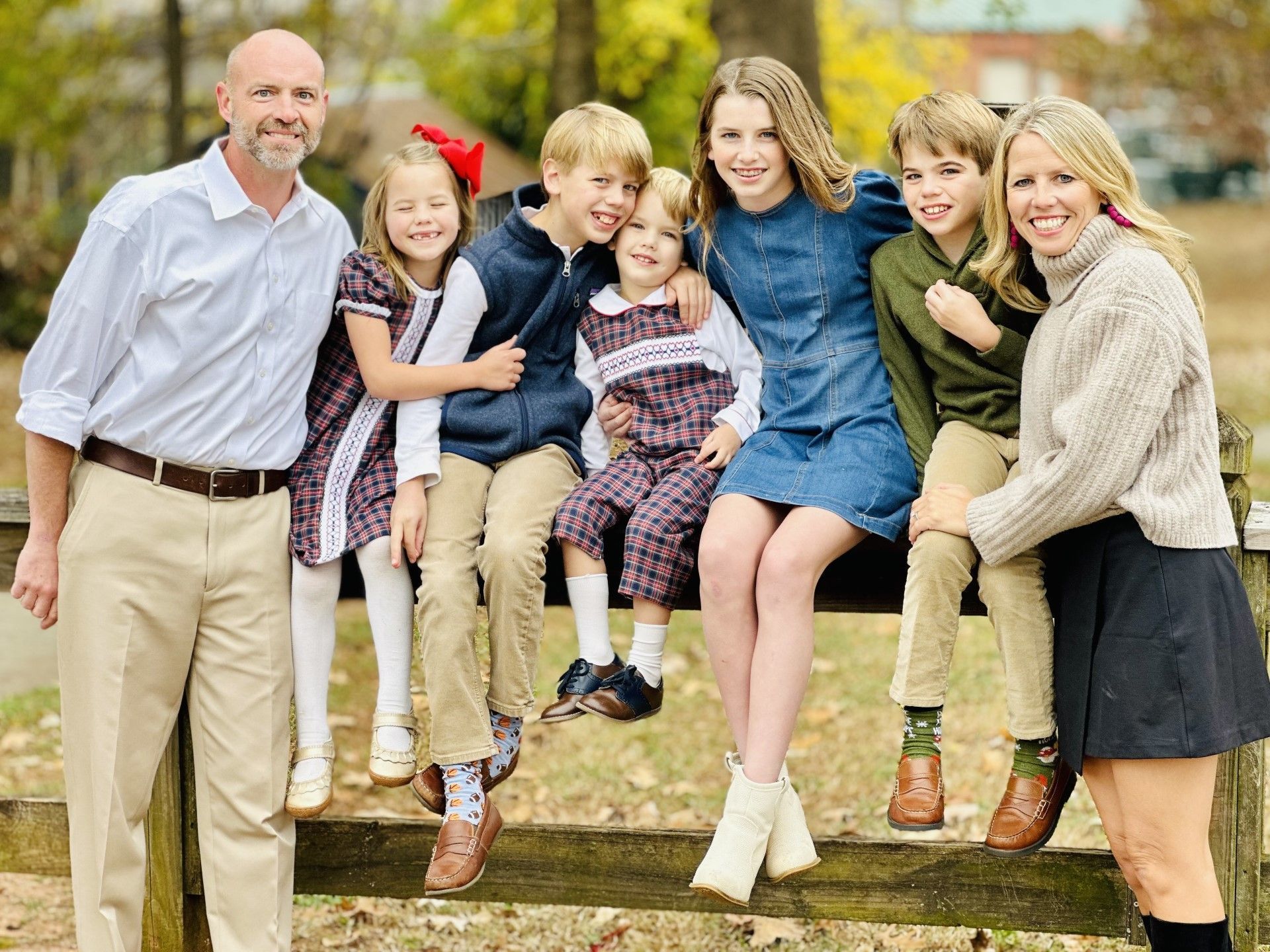 A family is posing for a picture while sitting on a fence.