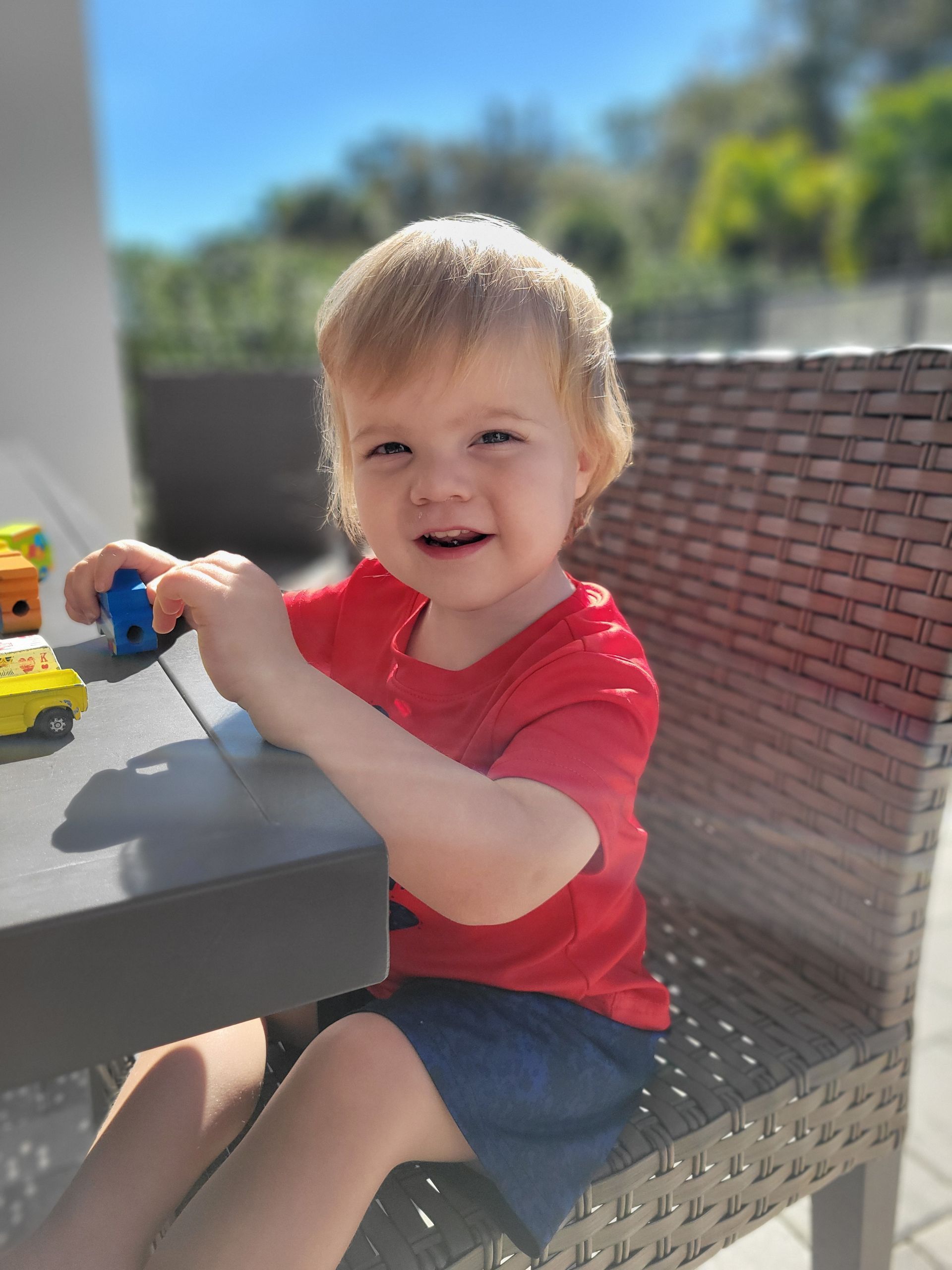 A little boy is sitting at a table playing with toys.