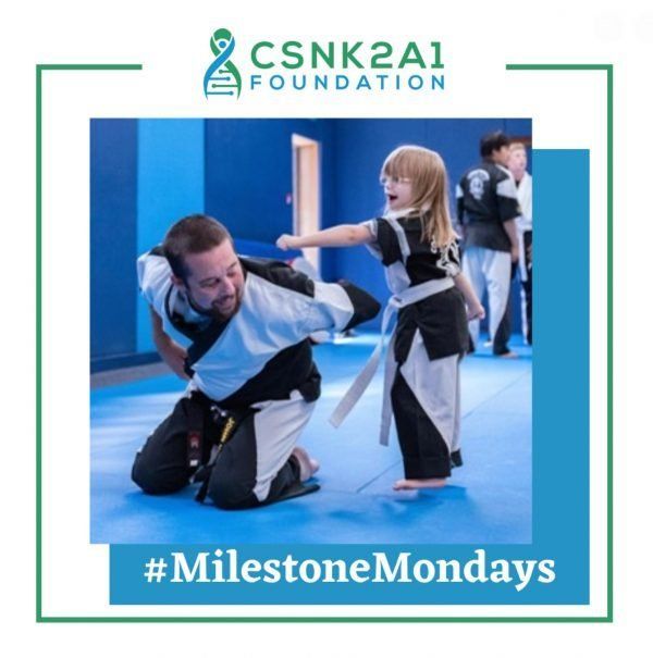 A picture of a man and a little girl kneeling on a blue mat with the words 