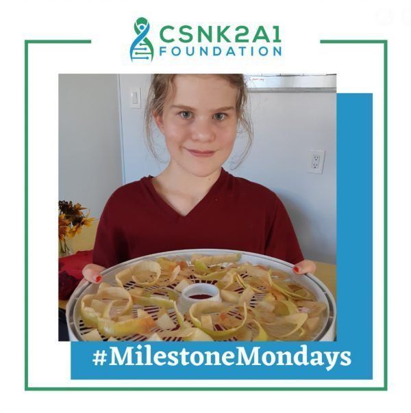 A young girl is holding a plate of food with the words milestone mondays below her