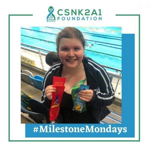 A woman is holding two ribbons in front of a swimming pool