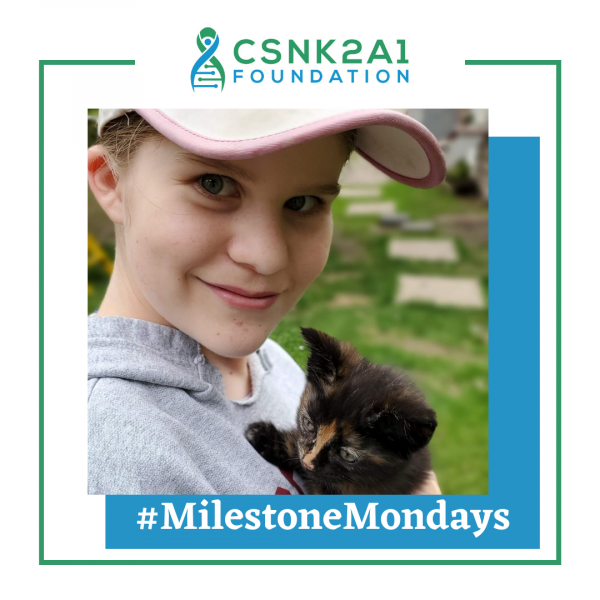 A young boy is holding a kitten in his arms with a csnk2a1 foundation logo in the background