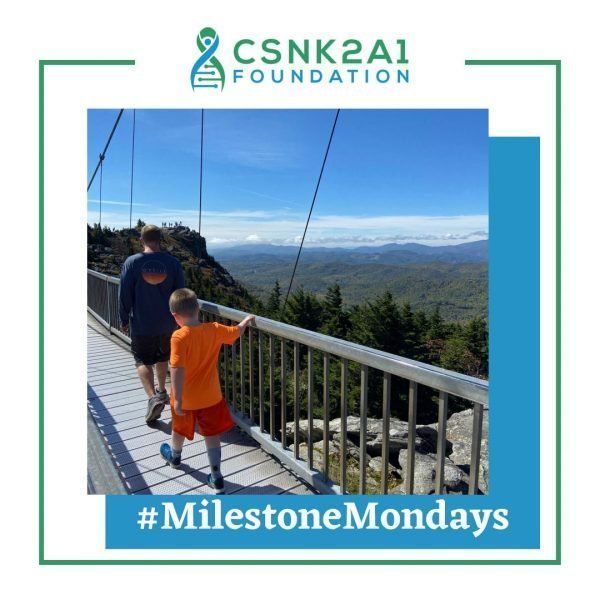 A man and a boy are walking across a bridge sponsored by the csnk2a1 foundation