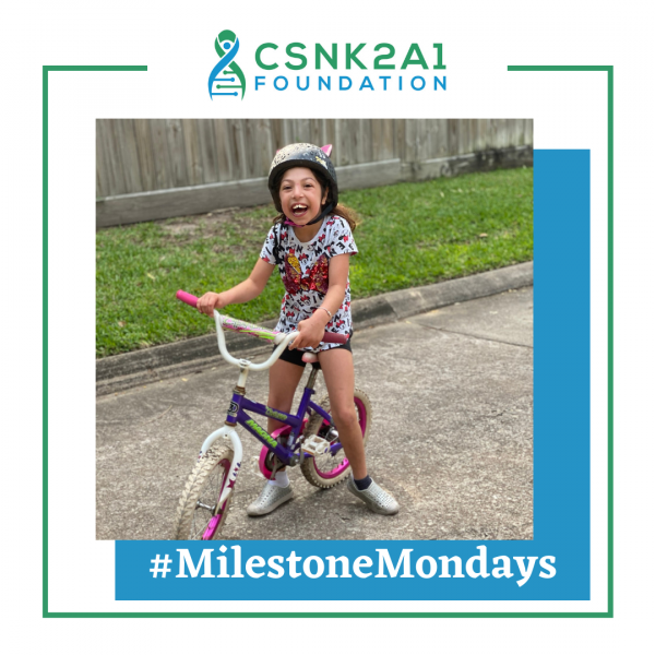 A little girl wearing a helmet is riding a bike