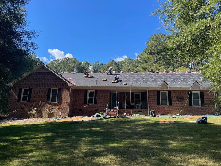 A large brick house with a roof that is being installed.