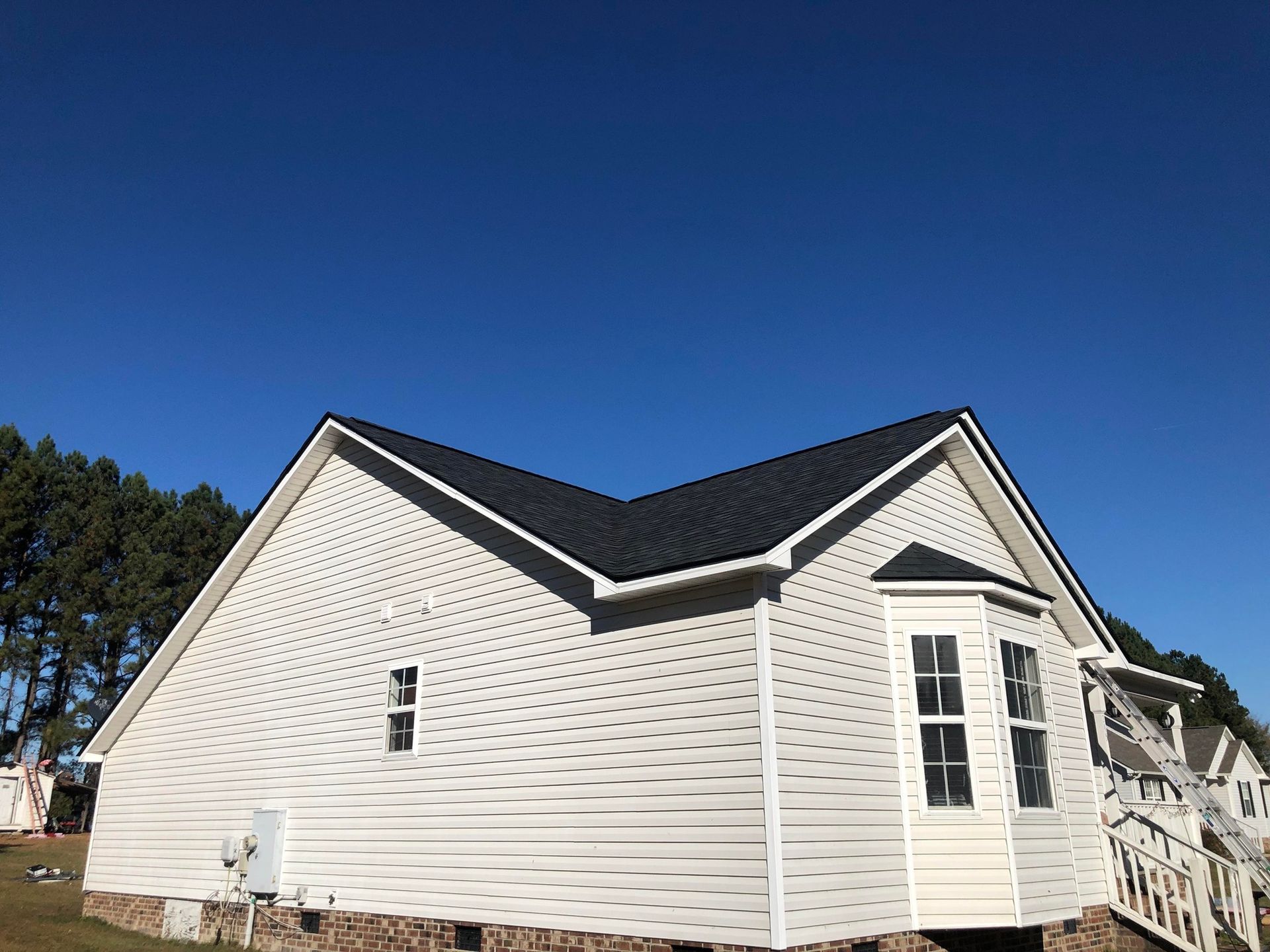 A white house with a black roof and a blue sky in the background.
