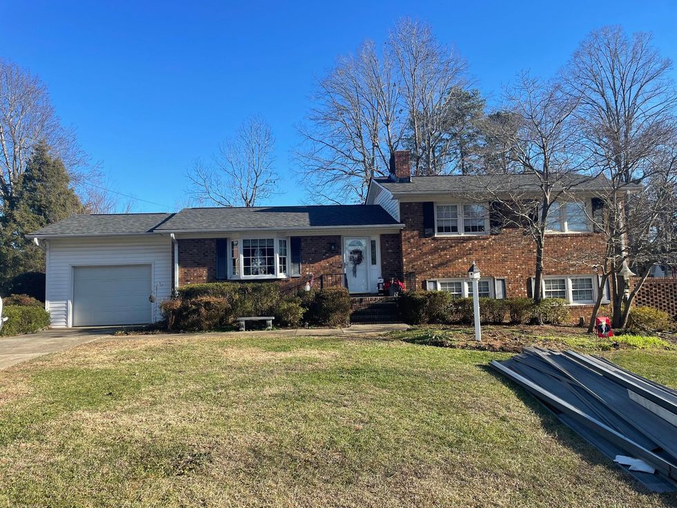 A brick house with a white garage door and a black roof.
