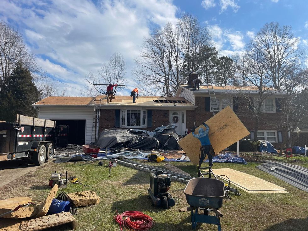 A group of people are working on the roof of a house.