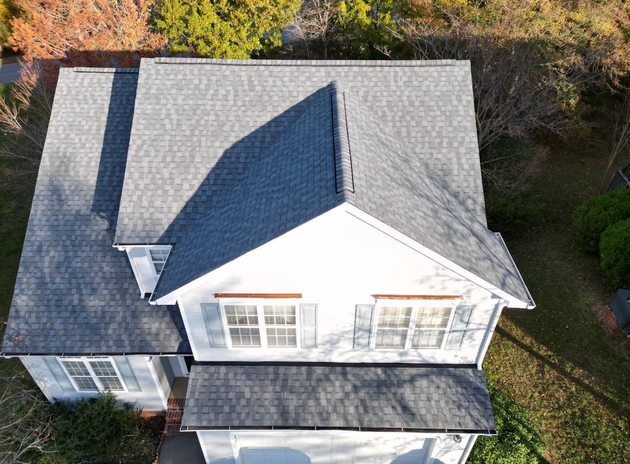 An aerial view of a white house with a gray roof.