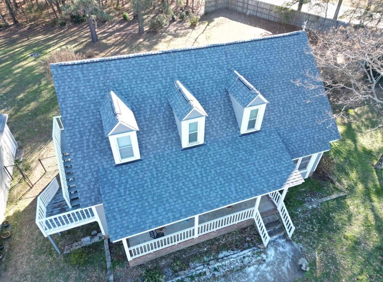 An aerial view of a house with three windows on the roof.