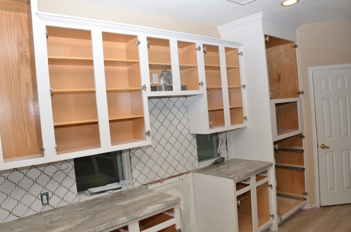 Kitchen with unfinished white cabinets, open shelving, tiled backsplash, and a small counter area