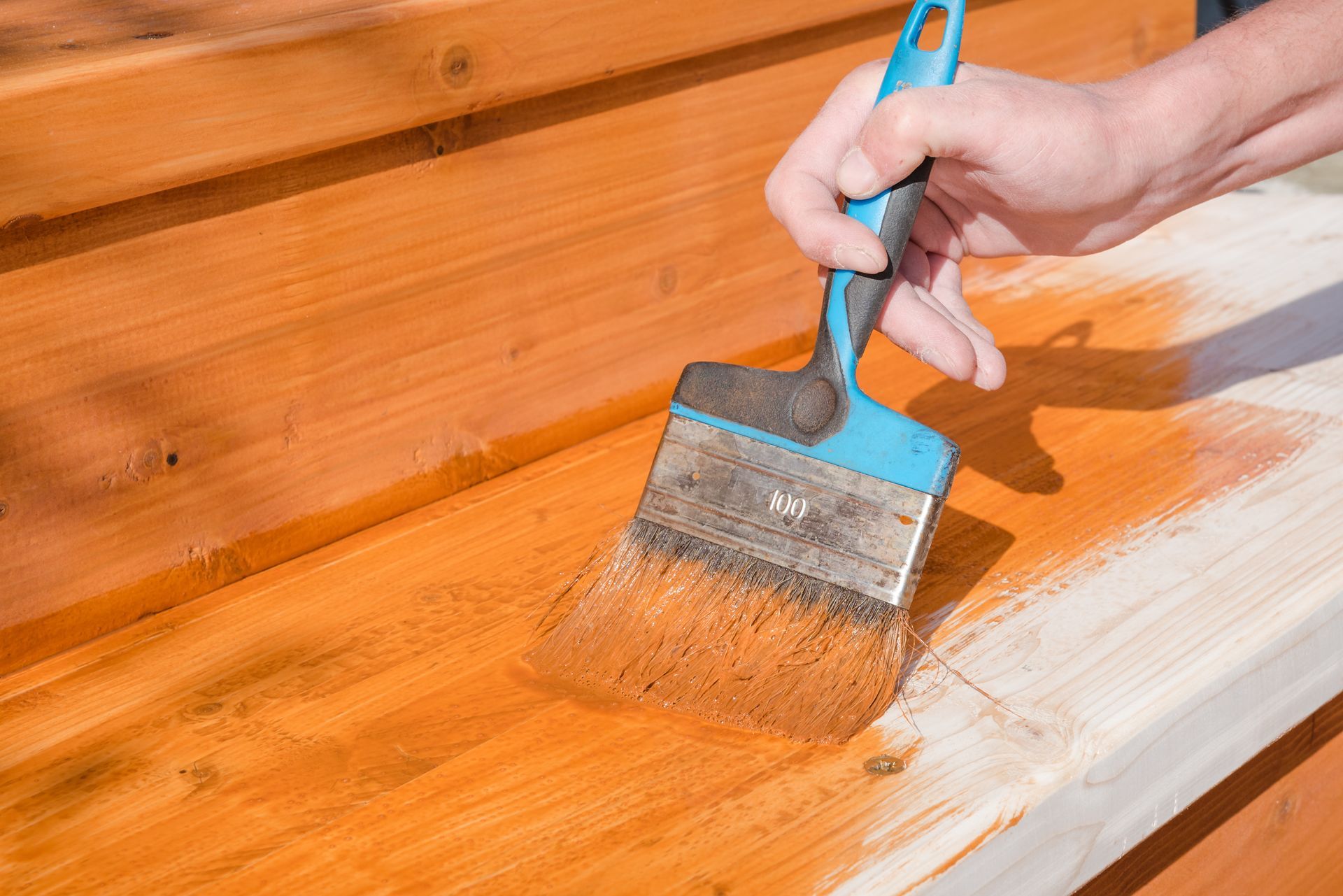 A person is painting a wooden surface with a brush.