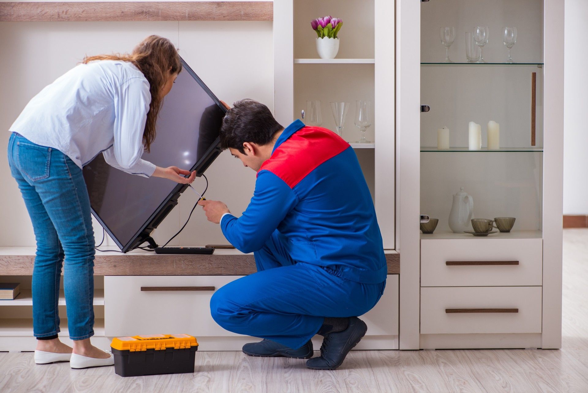 A man and a woman are fixing a flat screen tv in a living room.