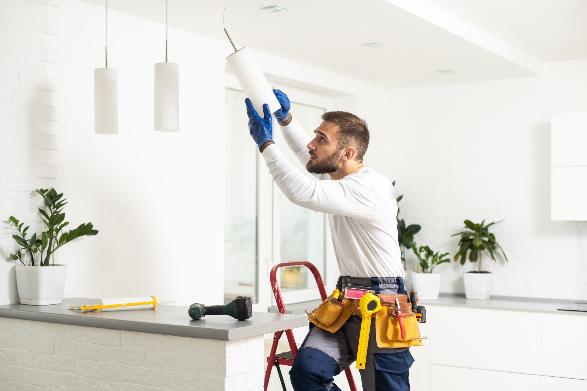 A man is installing a light fixture in a kitchen.