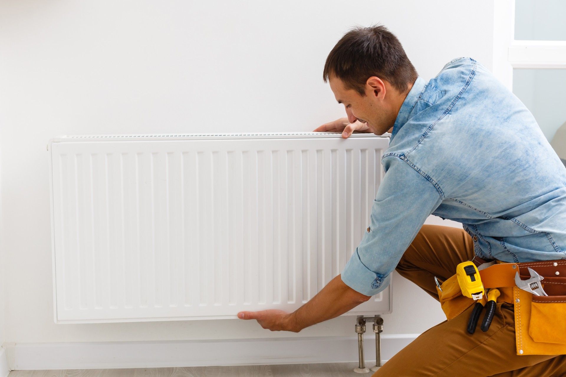 A man is working on a radiator in a room.