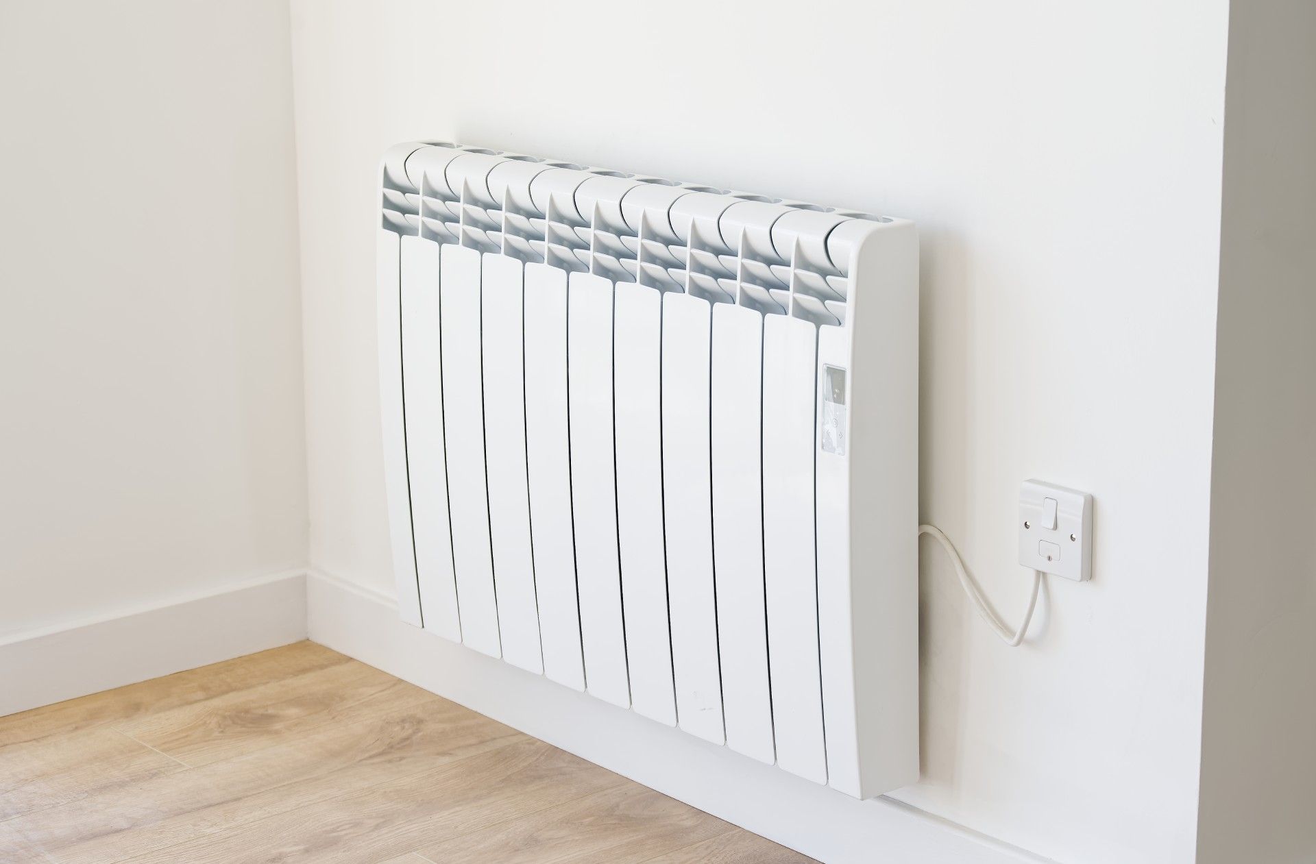 A white radiator is hanging on a white wall in a room.