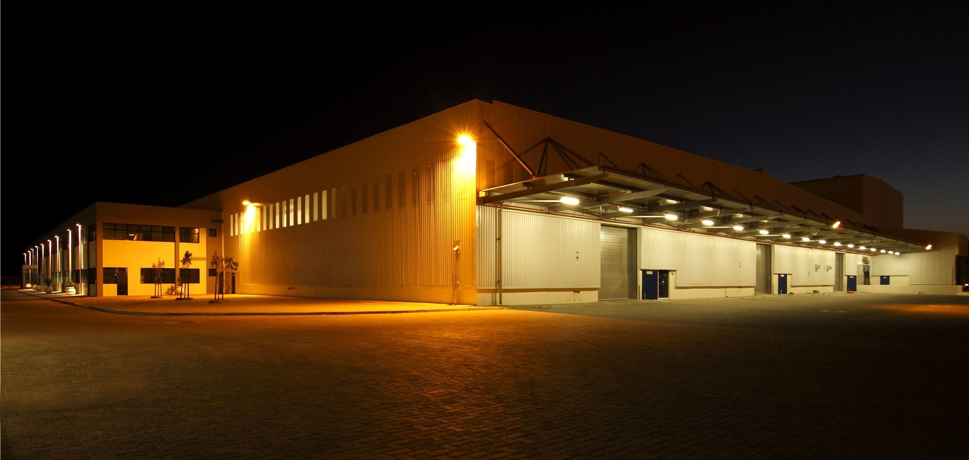 A large building is lit up at night in a parking lot.