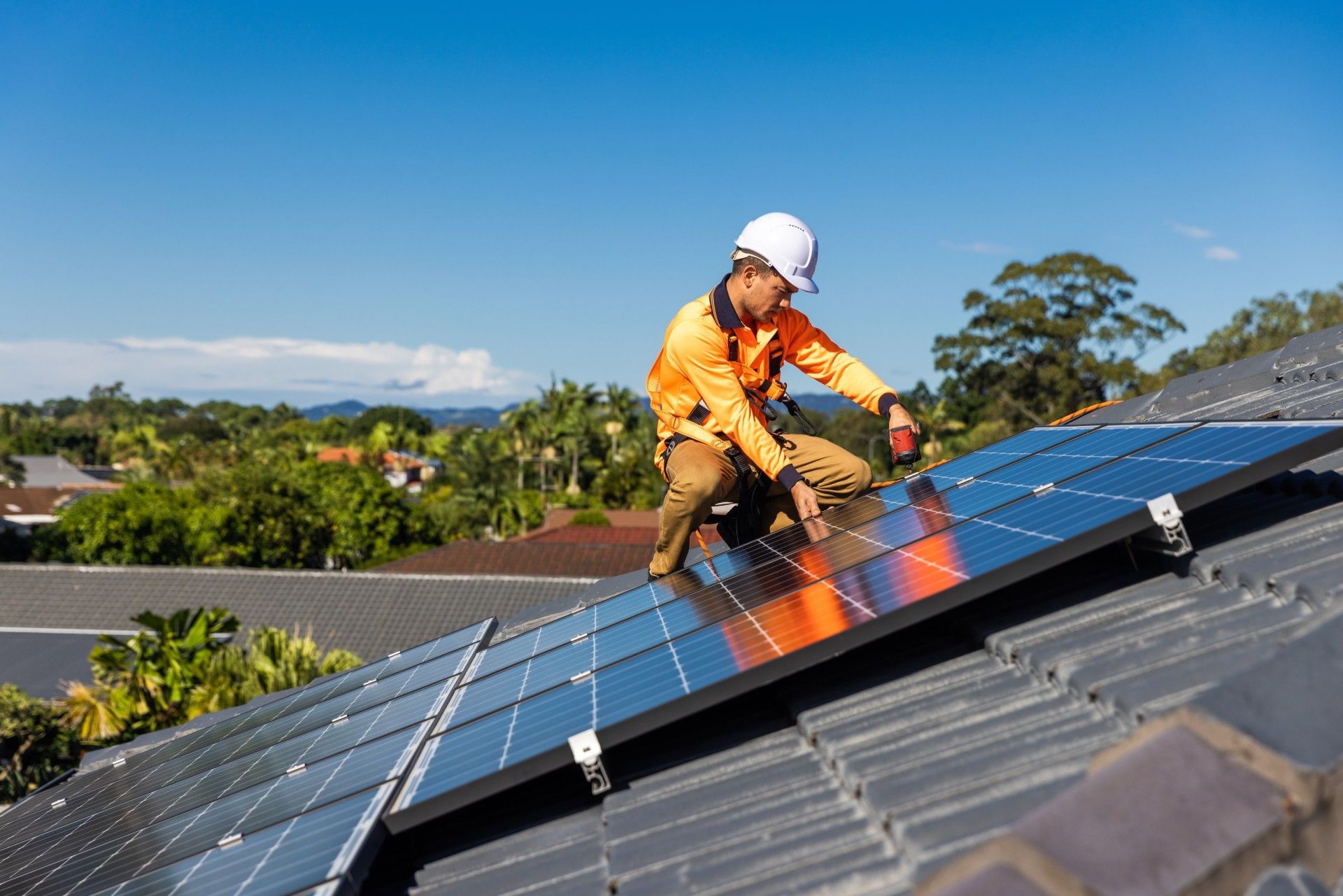 A man is installing solar panels on the roof of a house.