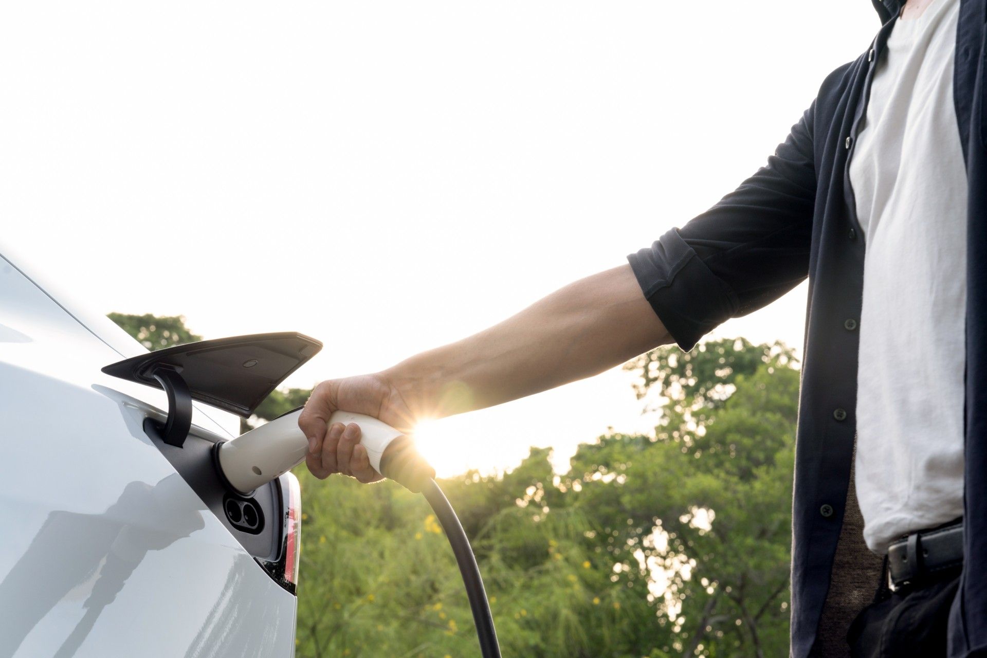 A man is charging an electric car at a charging station.