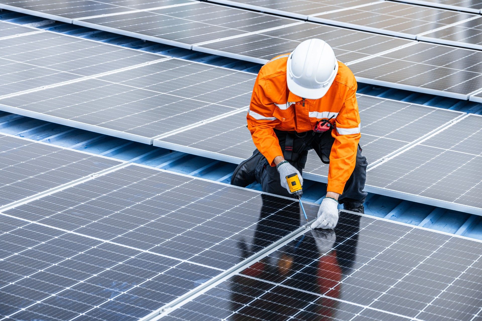 A man is installing solar panels on a roof.