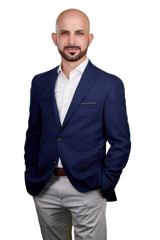 A man in a suit and tie is standing with his hands in his pockets.
