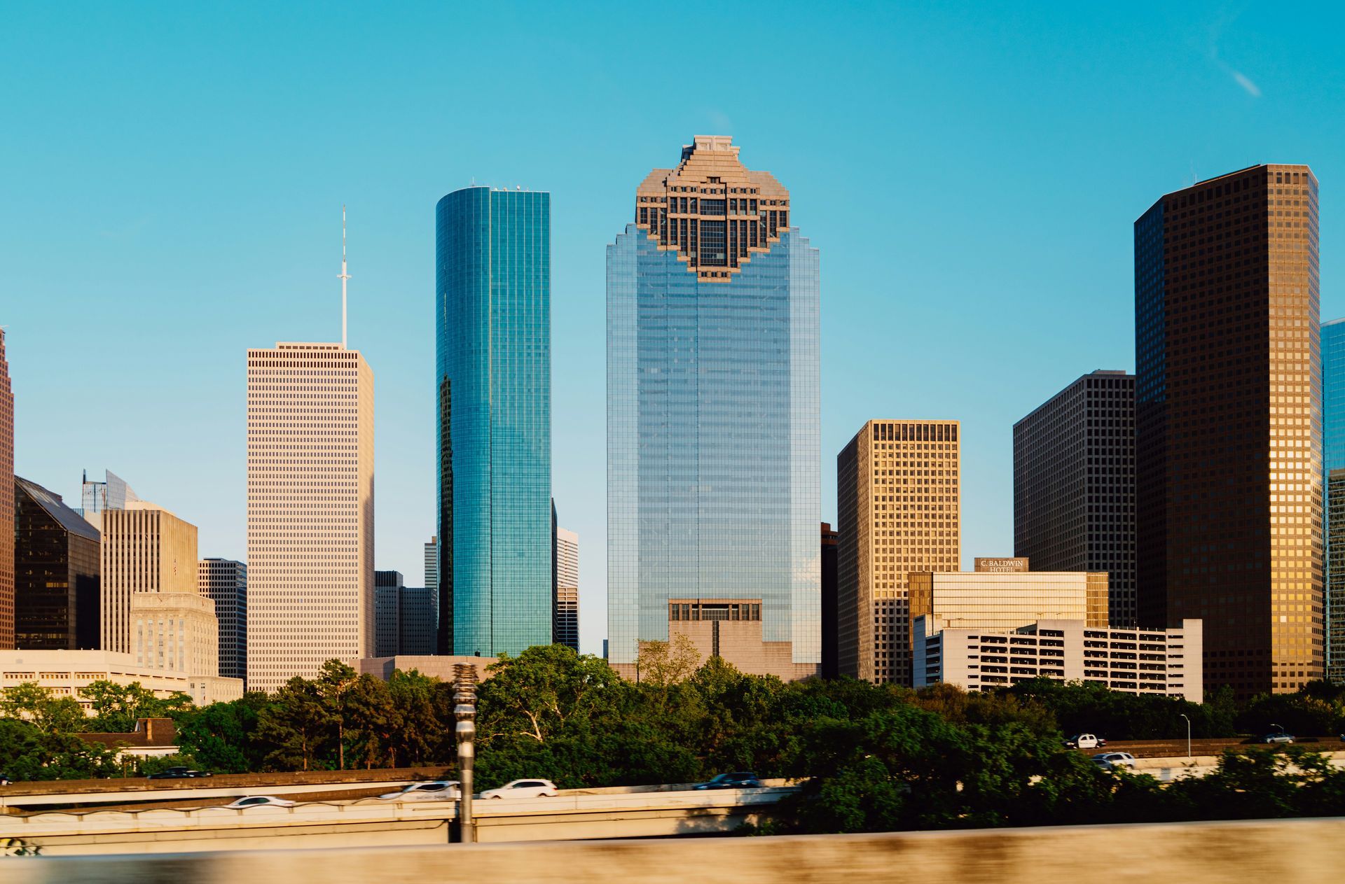 A city skyline with tall buildings and trees in the foreground