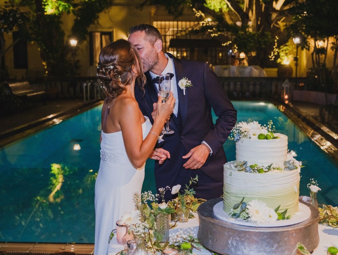 Una sposa e uno sposo si baciano davanti a una torta nuziale.