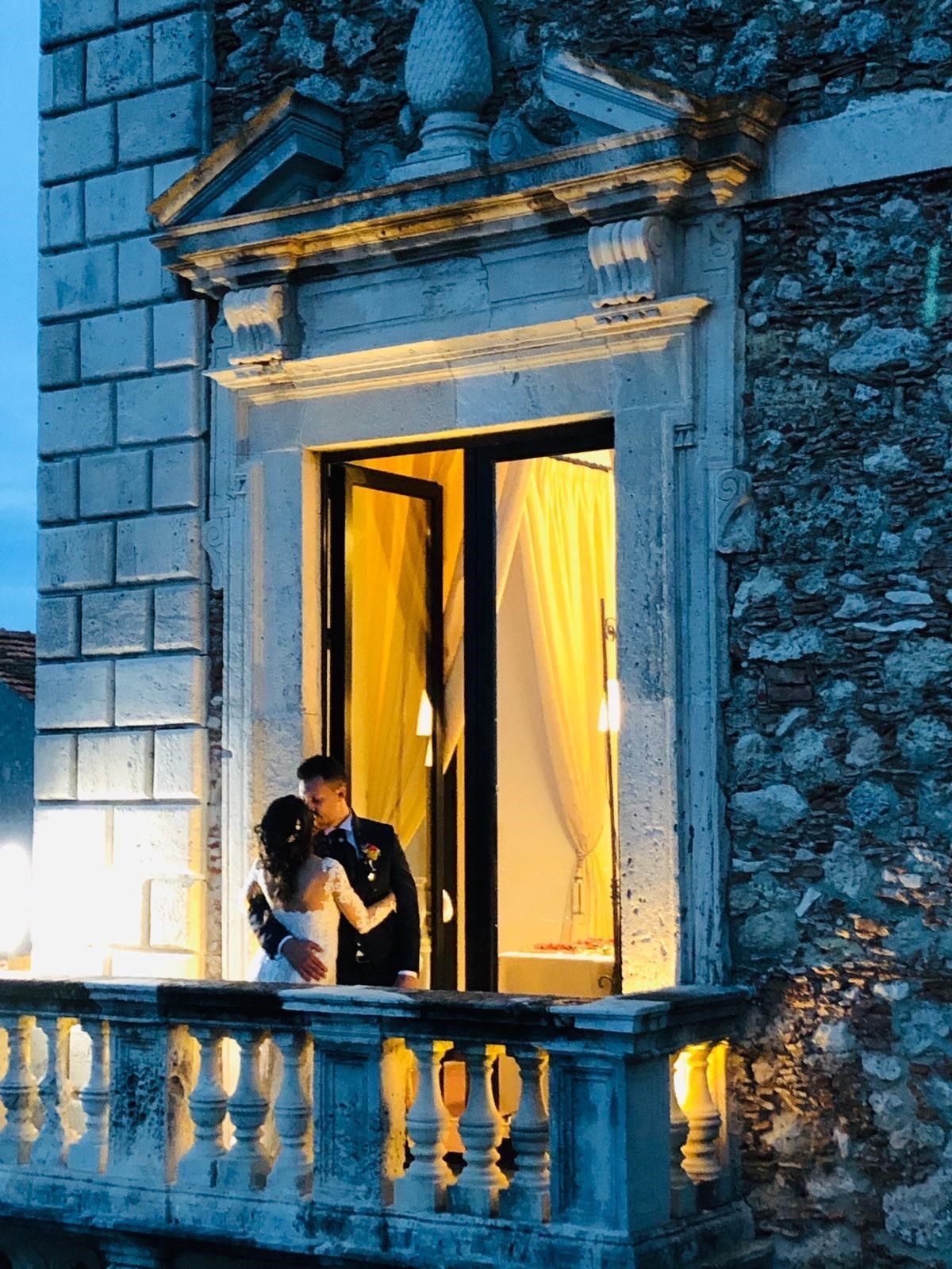 Una sposa e uno sposo si baciano sul balcone di un palazzo