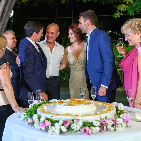 Un gruppo di persone in piedi attorno a una torta su un tavolo