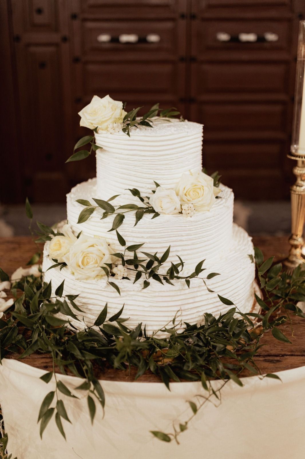 Una torta nuziale bianca è appoggiata su un tavolo di legno.