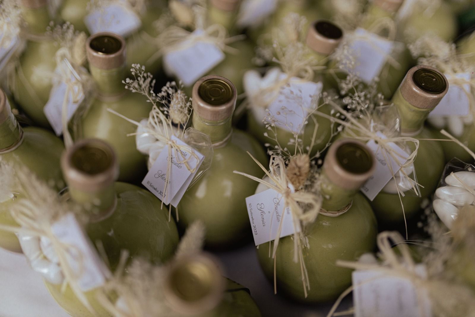 Un mucchio di bottiglie verdi con le etichette sono appoggiate su un tavolo.
