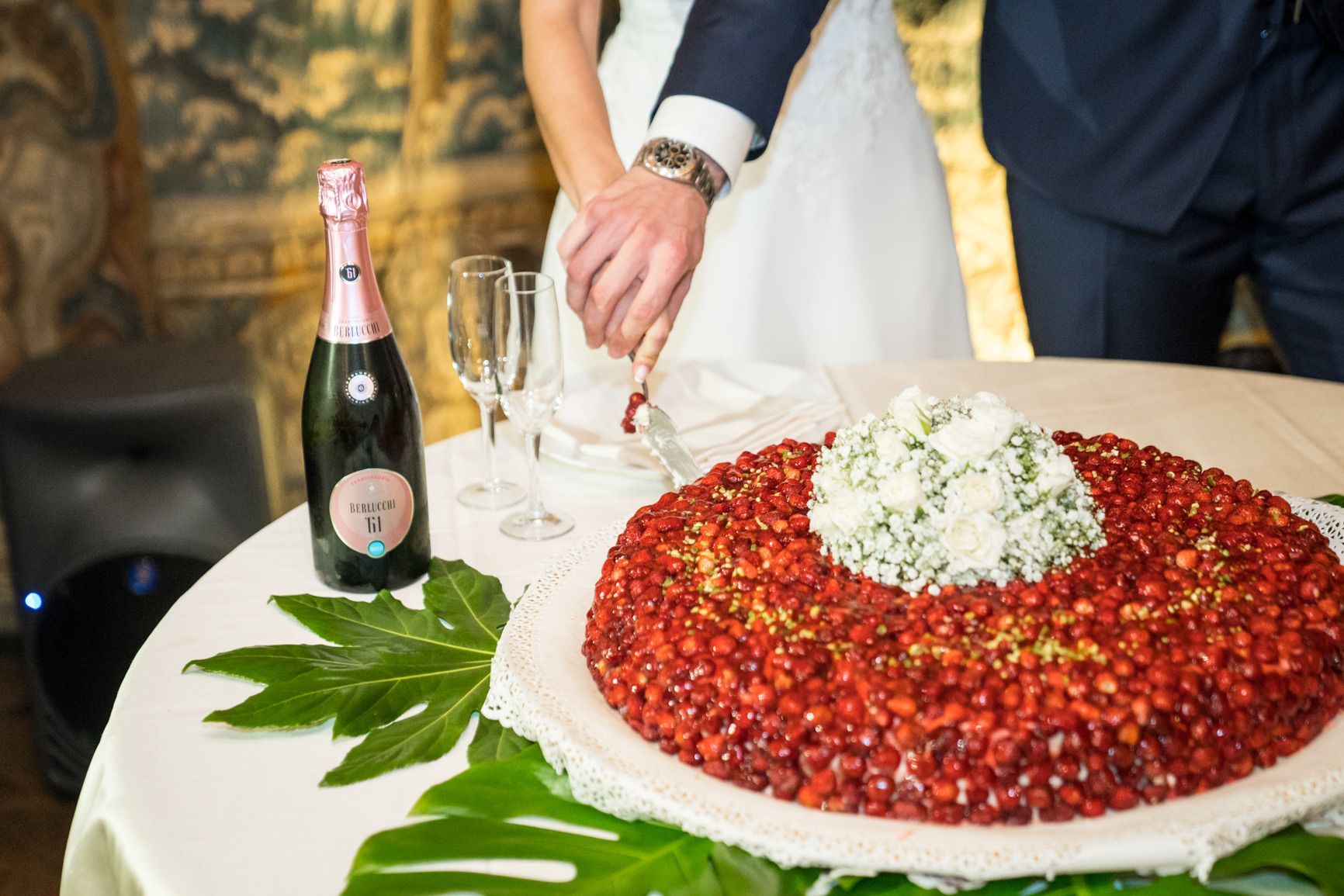 Gli sposi stanno tagliando la torta nuziale su un tavolo.