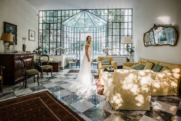 Una donna in abito da sposa è in piedi in un soggiorno.