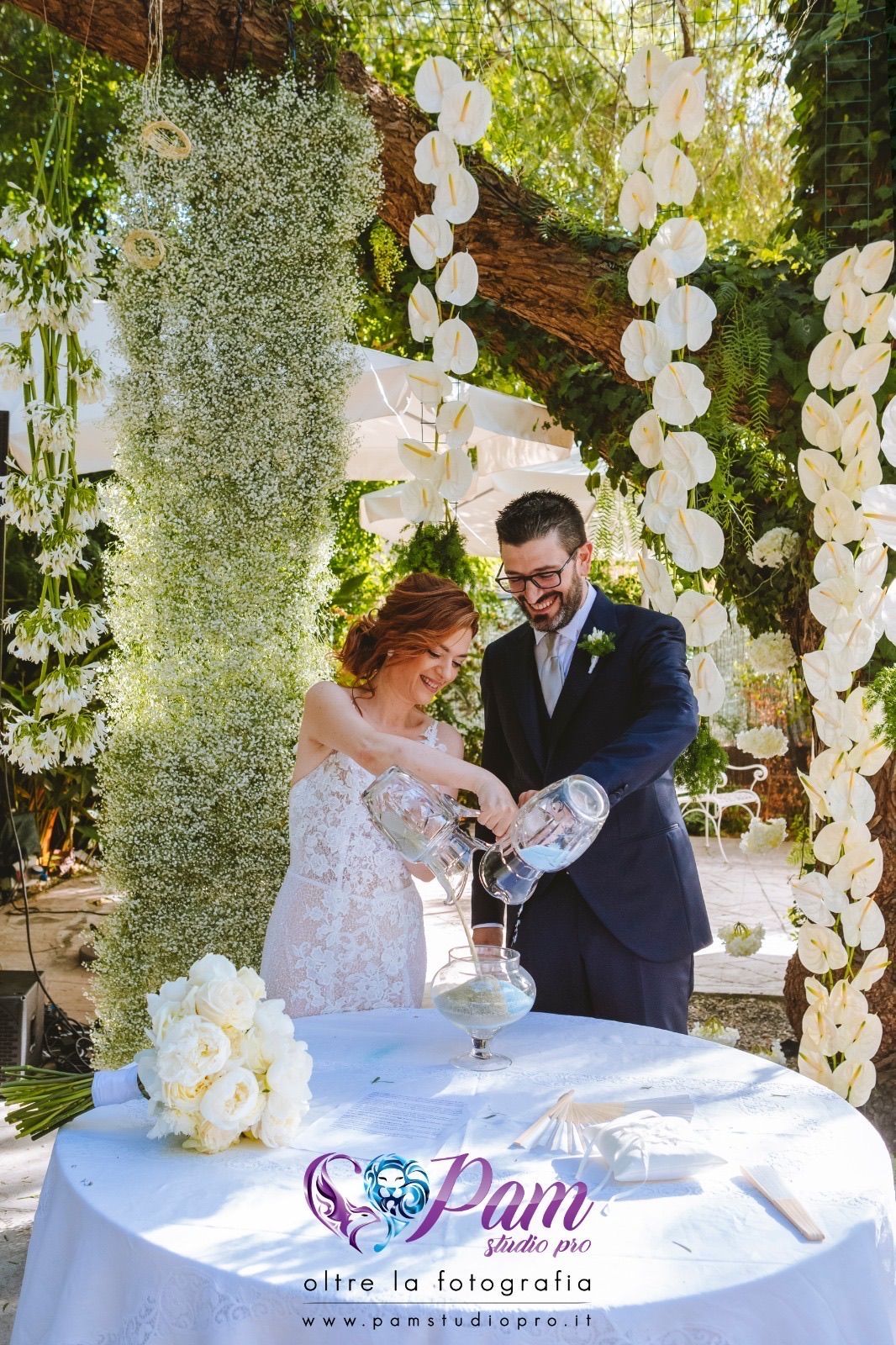 Una coppia di sposi versa dell'acqua in un bicchiere durante la cerimonia delle loro nozze.
