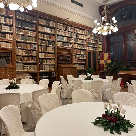 Una grande stanza con tavoli e sedie di fronte a una parete di libri