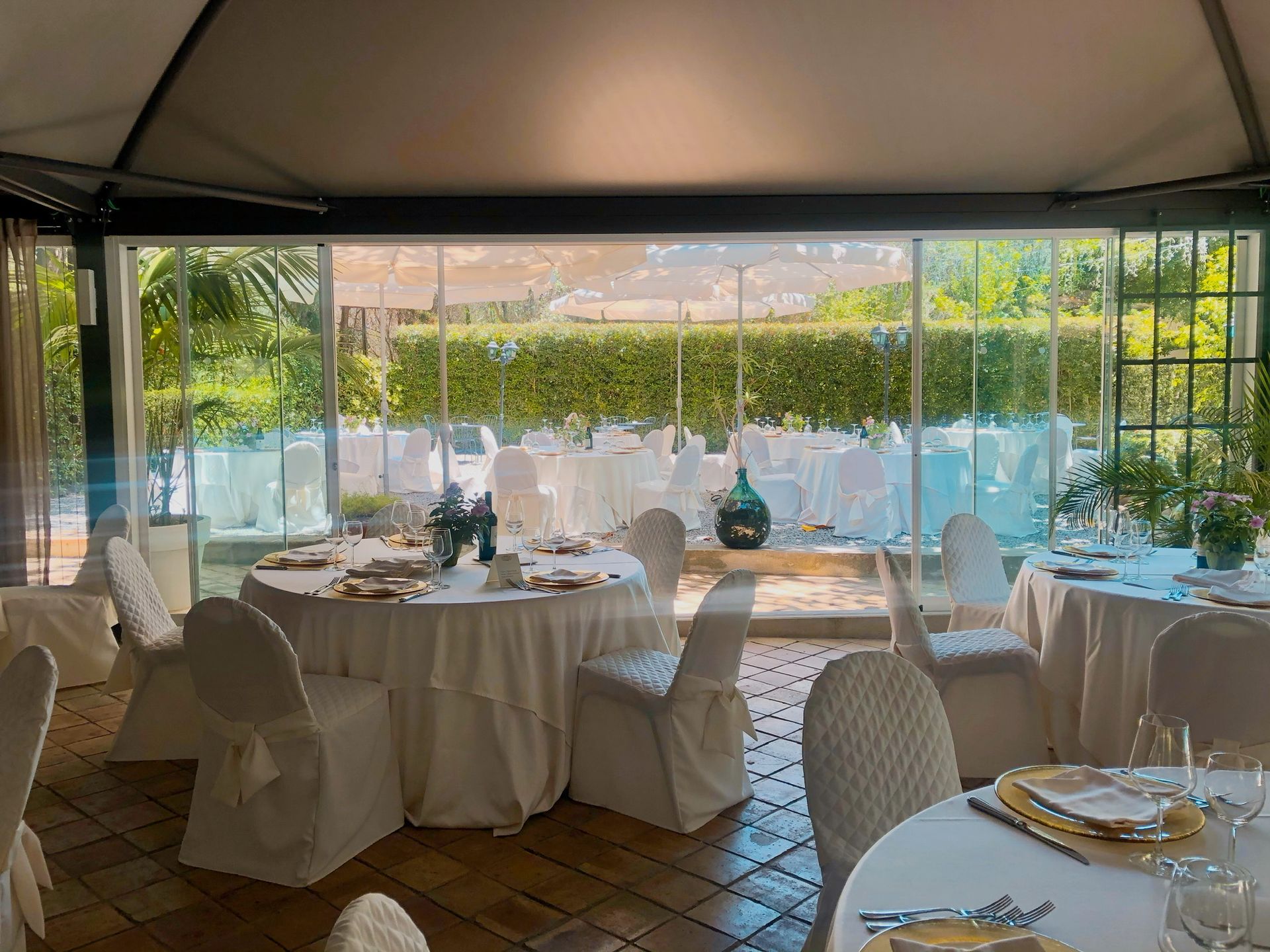 Una stanza con tavoli e sedie allestita per un ricevimento di nozze.