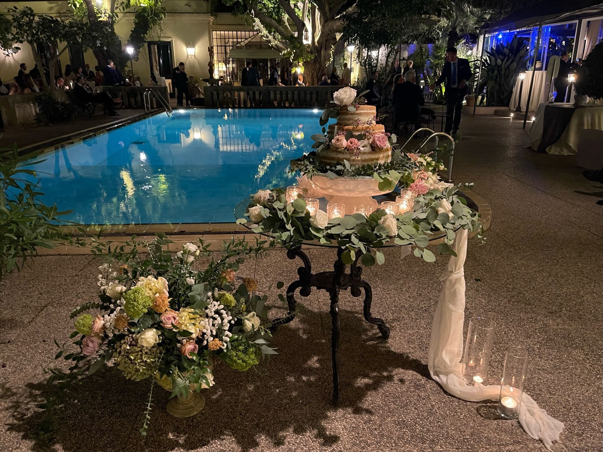 Una torta nuziale è appoggiata su un tavolo di fronte a una piscina.
