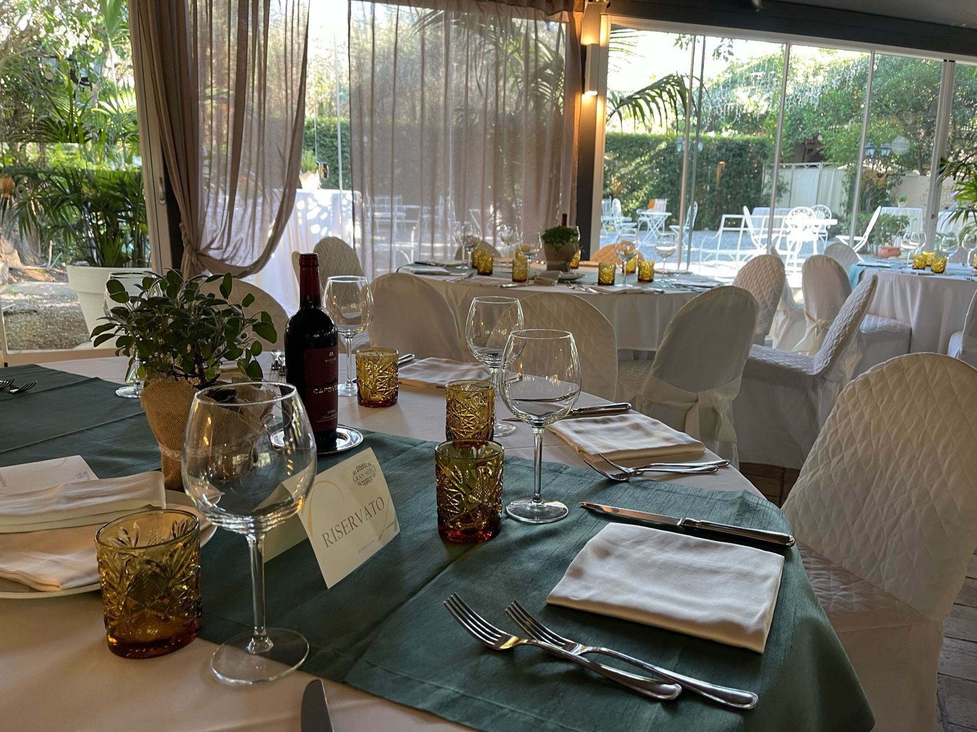 Un tavolo apparecchiato per un ricevimento di nozze con sopra una bottiglia di vino.