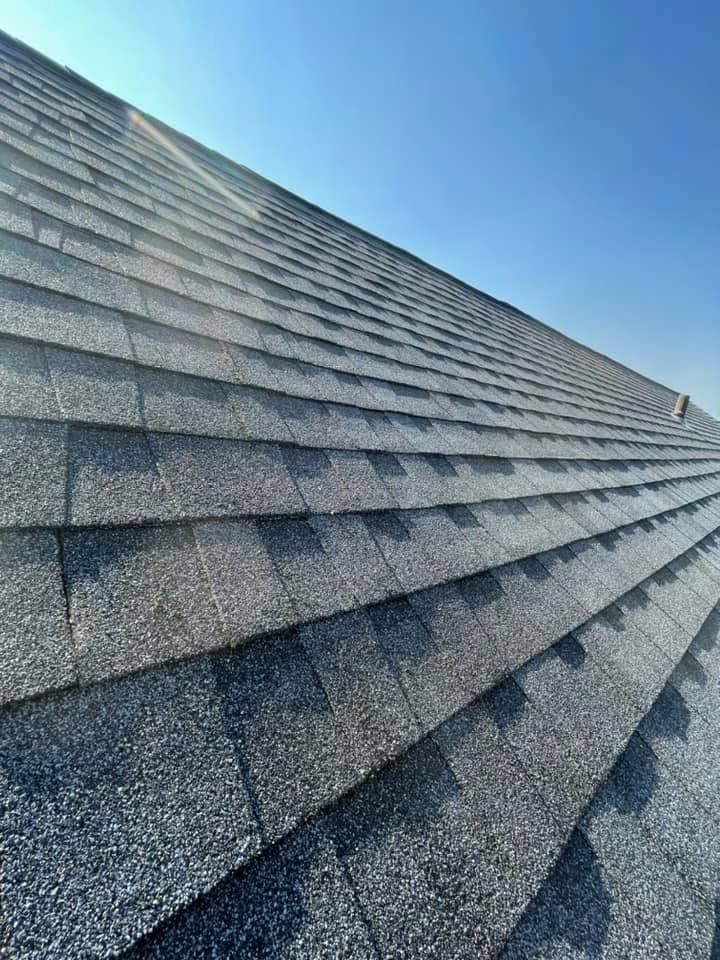 A close up of a roof with shingles and a blue sky in the background.