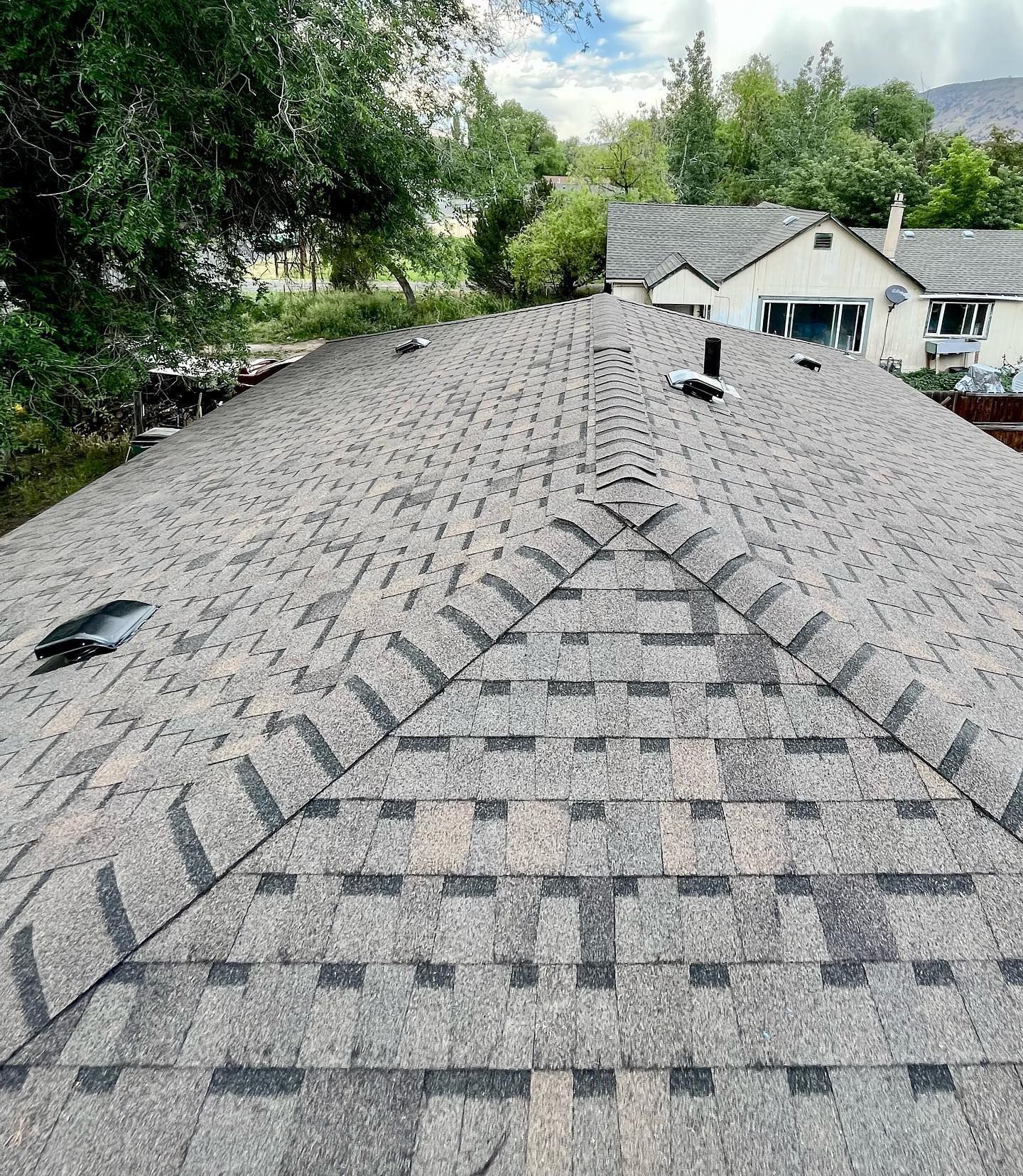 A roof with a lot of tiles on it and a house in the background.
