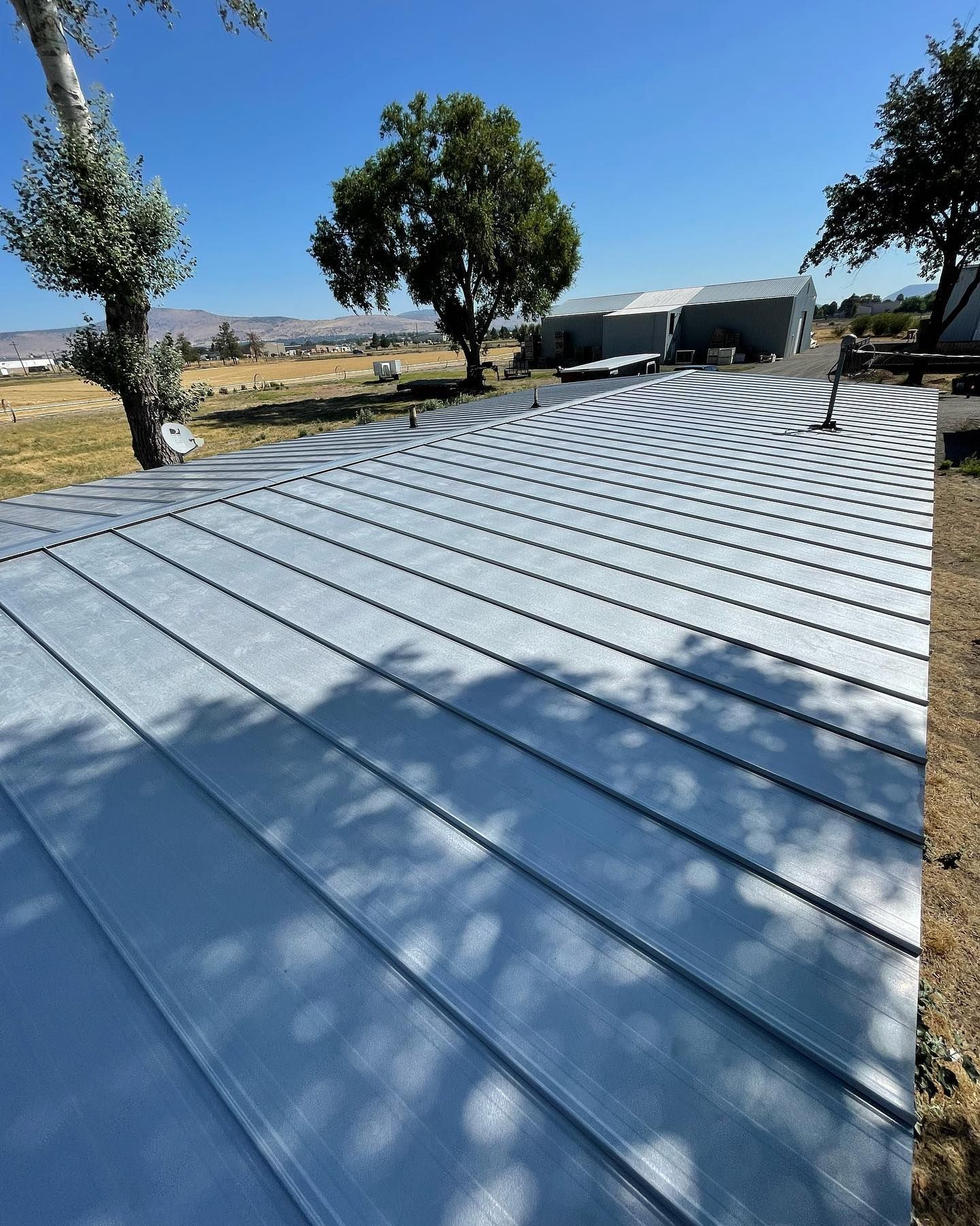 A metal roof is sitting on top of a dirt field with trees in the background.
