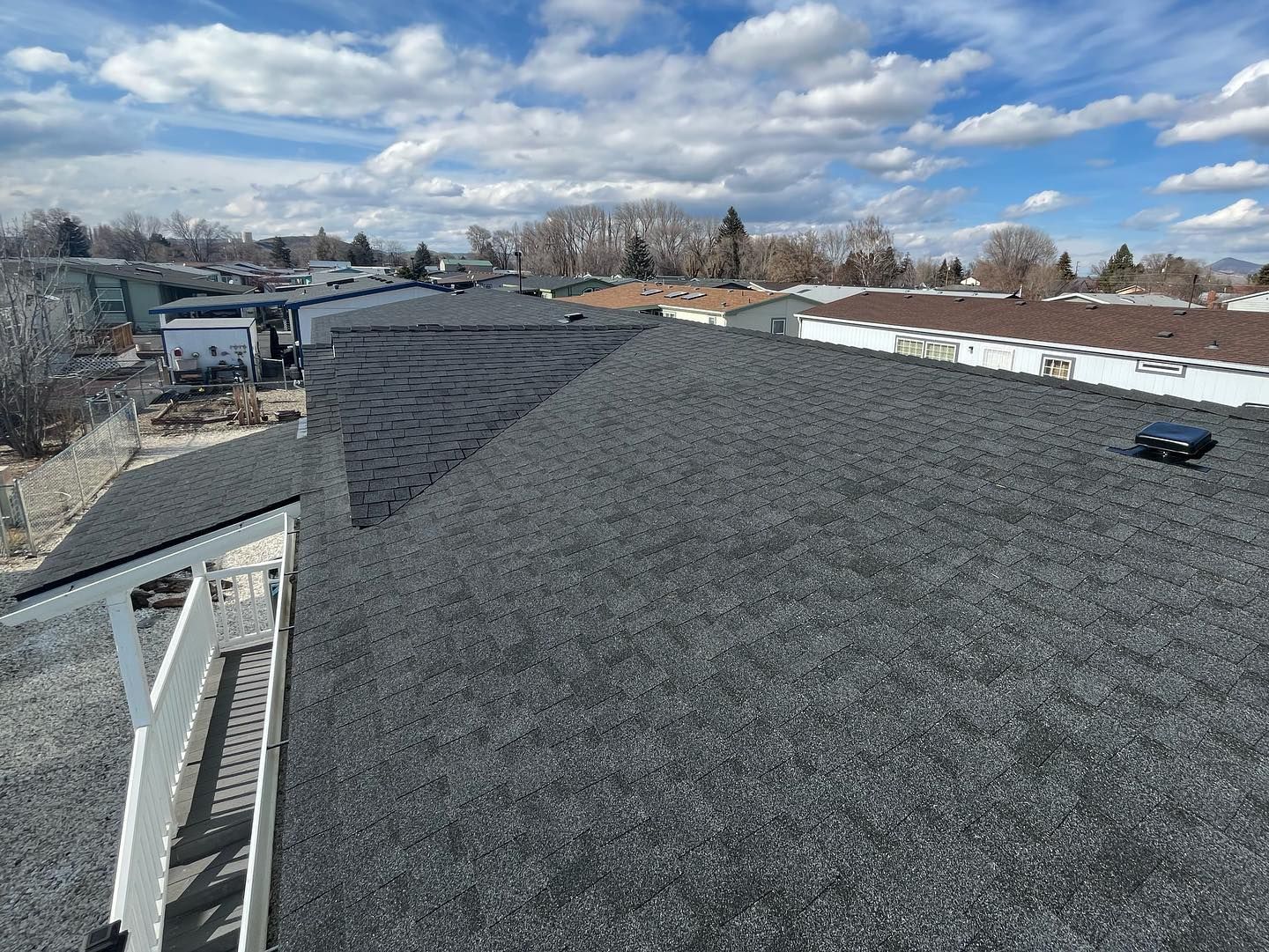 An aerial view of a roof with a blue sky and clouds in the background.