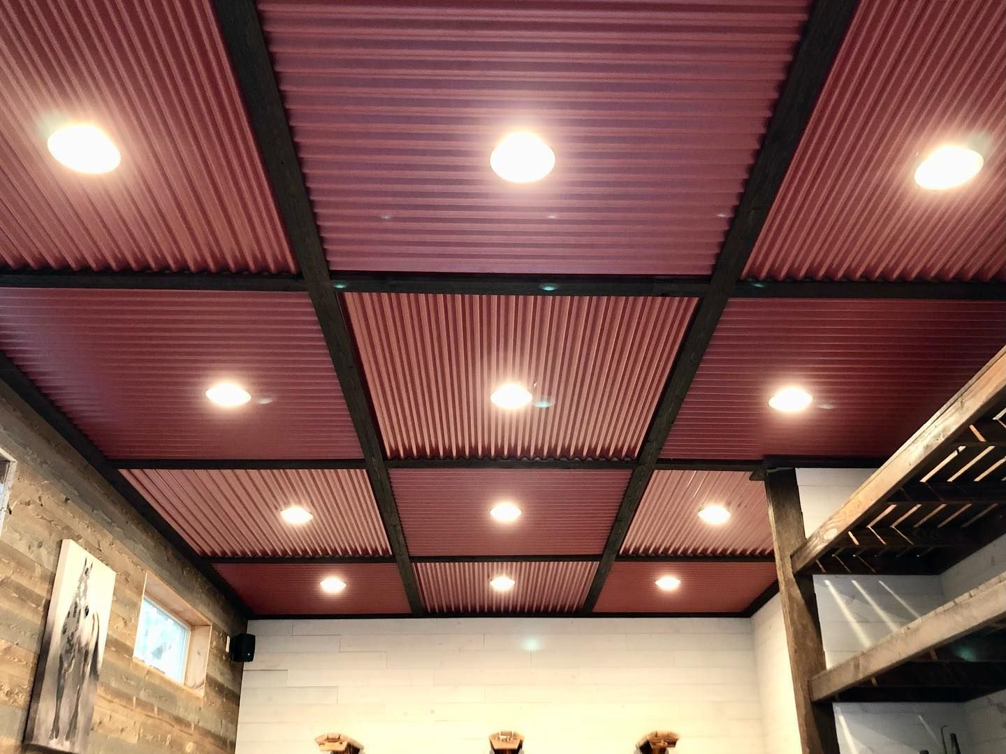 A red corrugated metal ceiling with lights on it in a room.