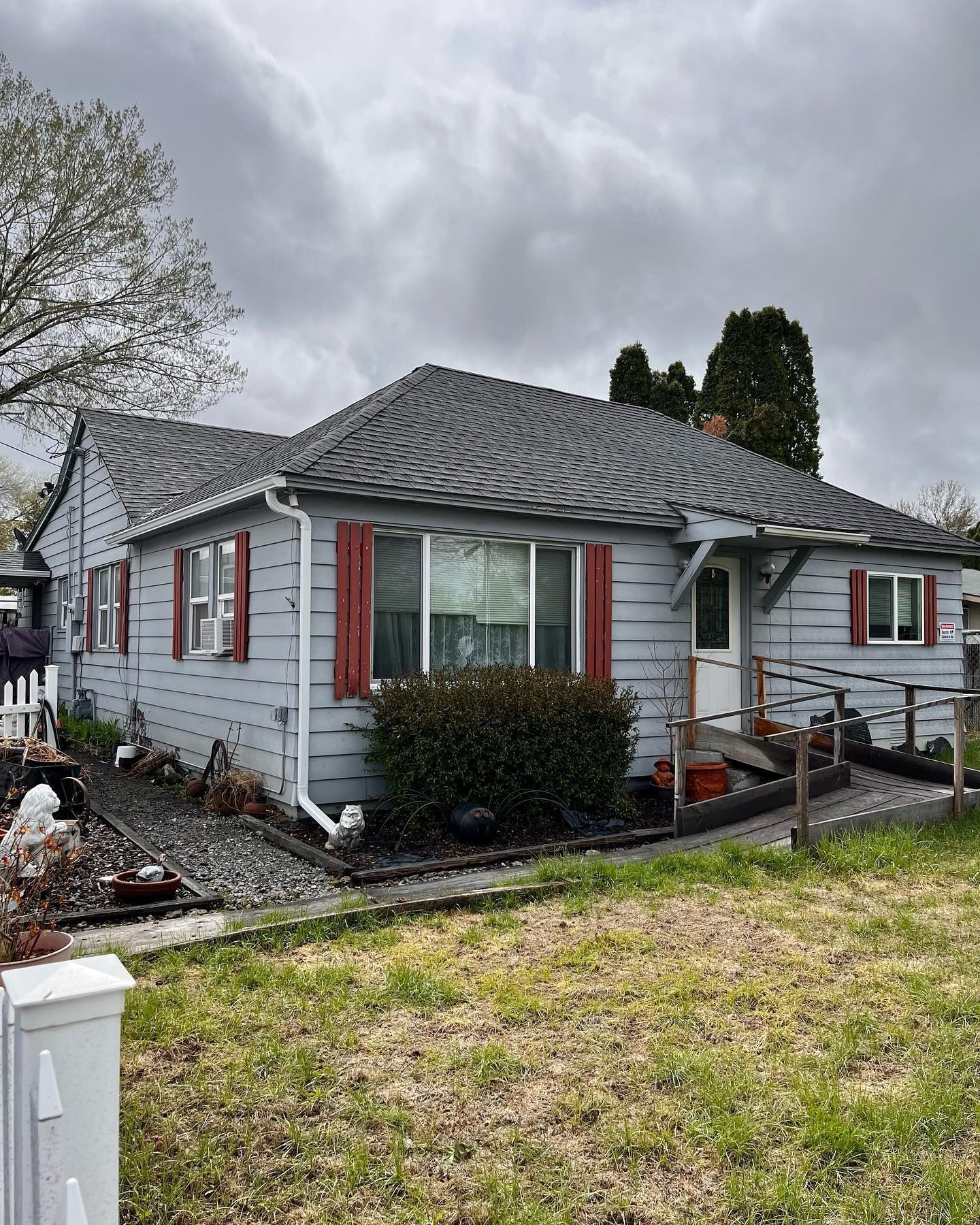 A small house with a gray roof and red shutters
