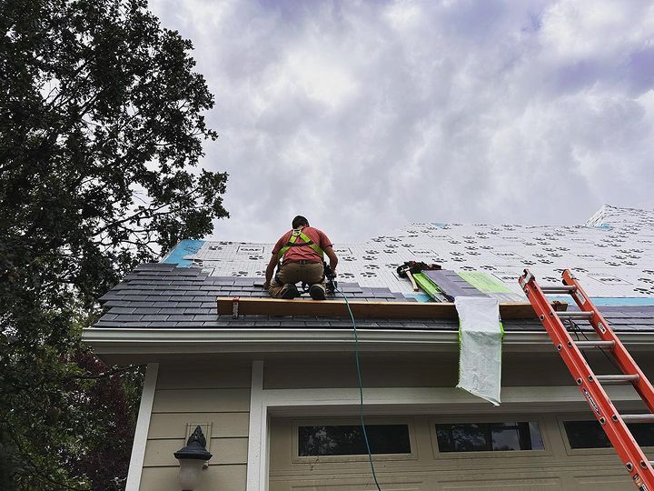 A man is working on the roof of a house.