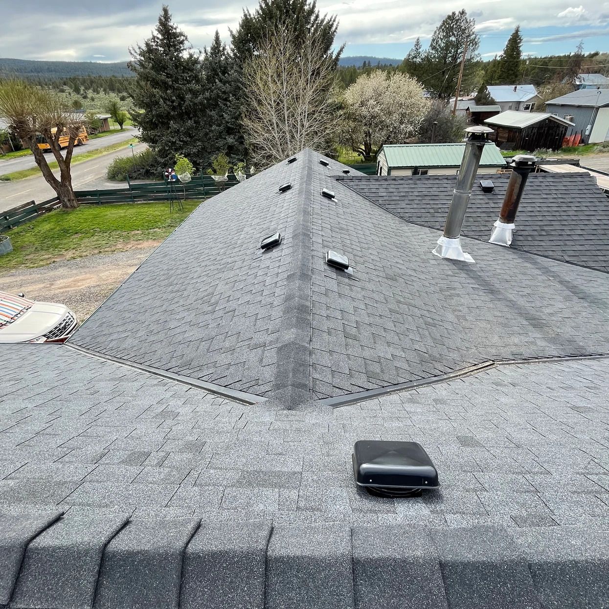 A roof with a chimney on top of it and trees in the background.