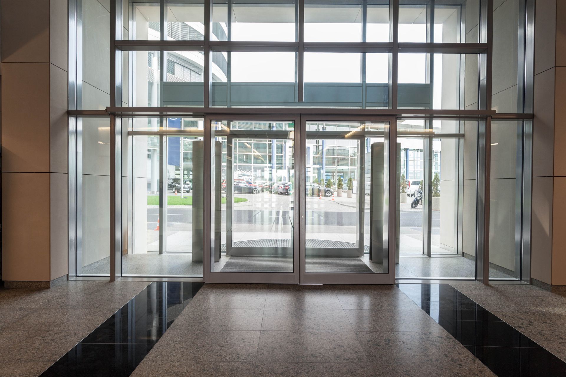 An empty lobby of a large building with sliding glass doors.