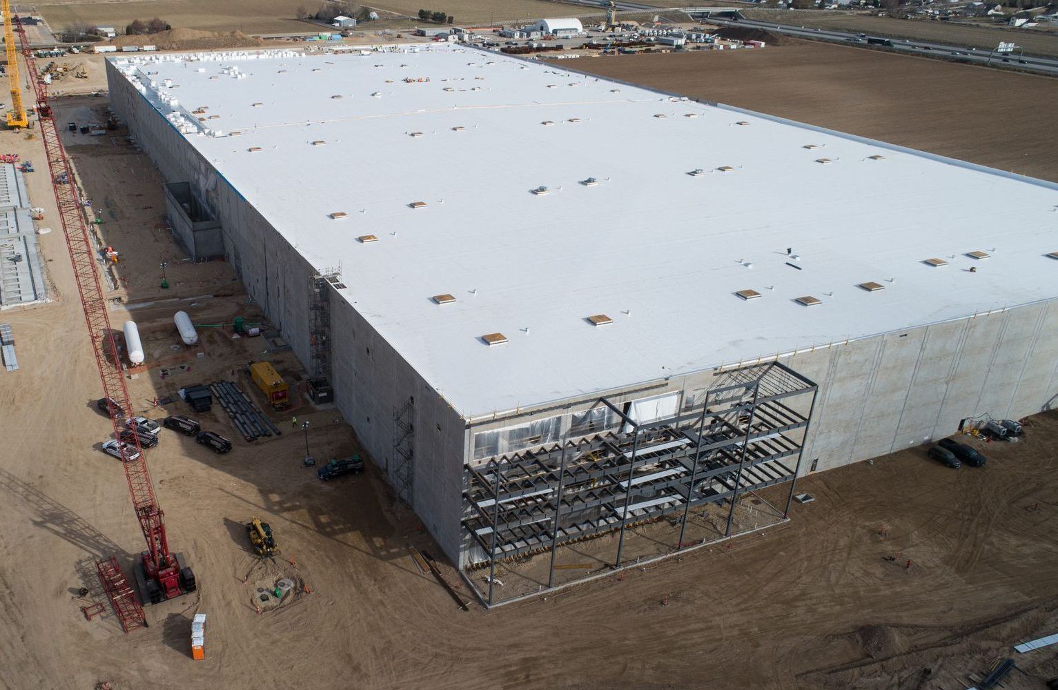 An aerial view of a large building under construction with a white roof.